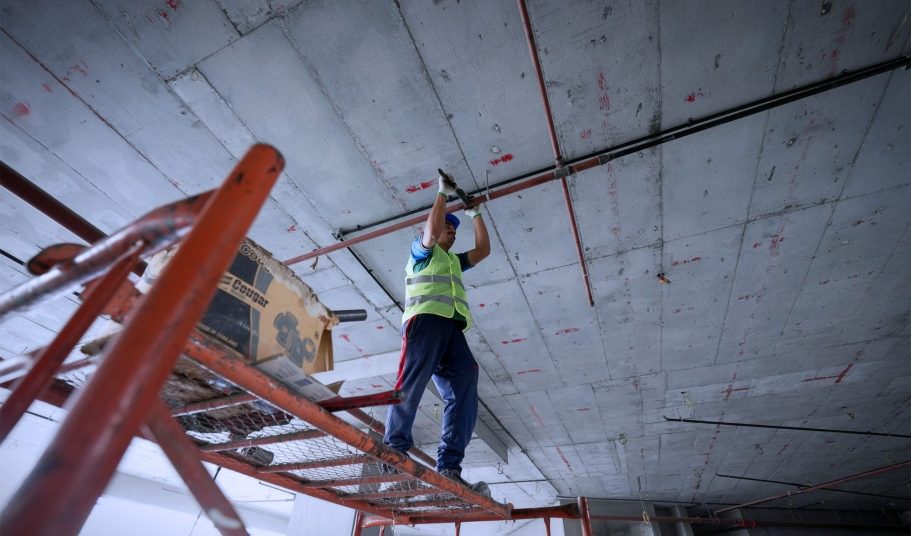Man on scaffolding Man standing on scaffolding fixing a pipe on the ceiling